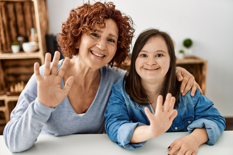 Resident and staff member smiling and waving